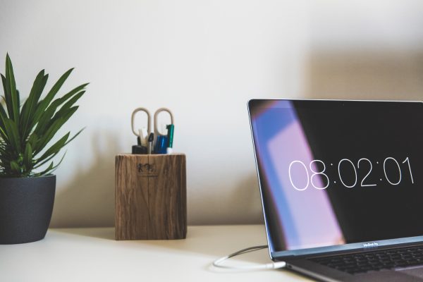 Escritorio de mesa y ordenador con reloj en pantalla - Distribución irregular de la jornada - AYCE Laborytax Distribución irregular de la jornada
